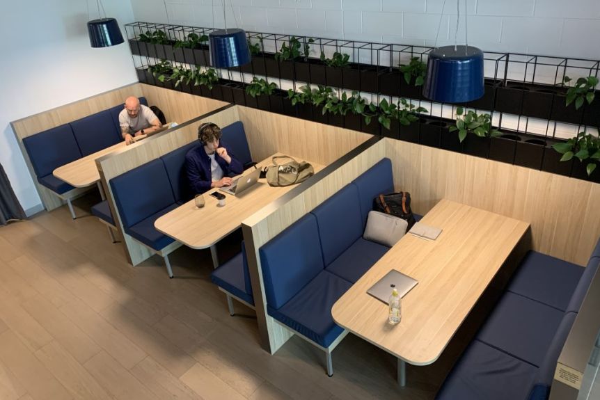 Une rangée de trois tables dans un café avec deux personnes travaillant.
