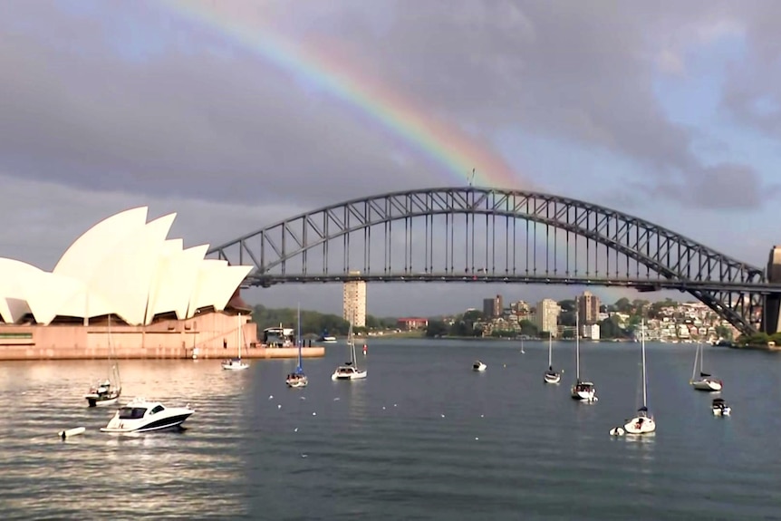 Un arc-en-ciel sur le Sydney Harbour Bridge avec des bateaux sur l'eau